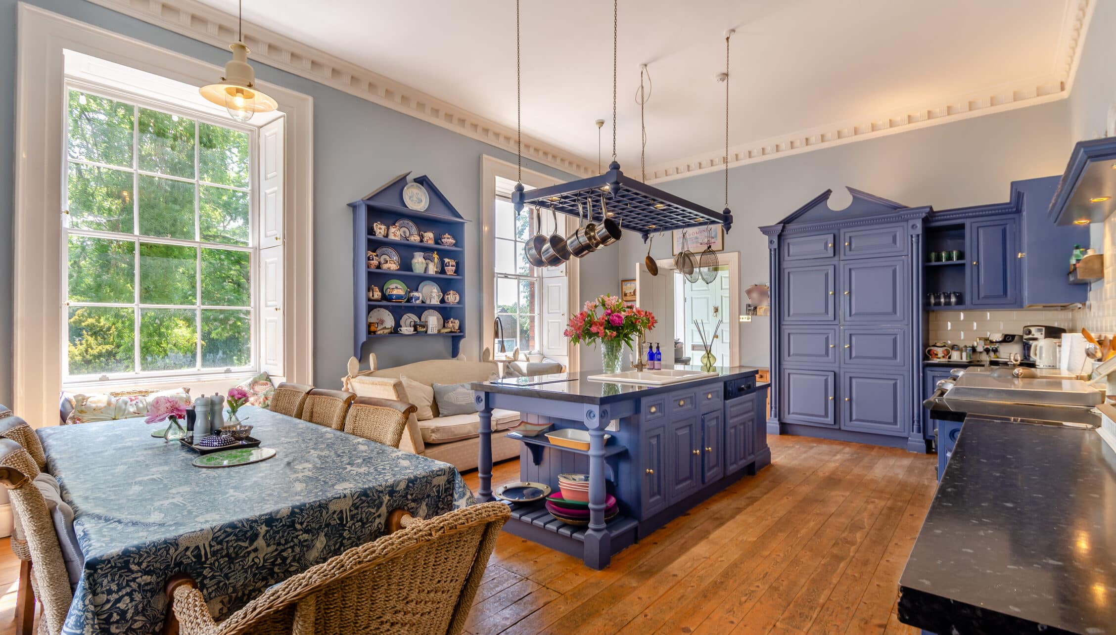 Breedon Hall, Leicestershire – Kitchen and dining area with navy cabinetry, hanging cookware rack, and window seat.