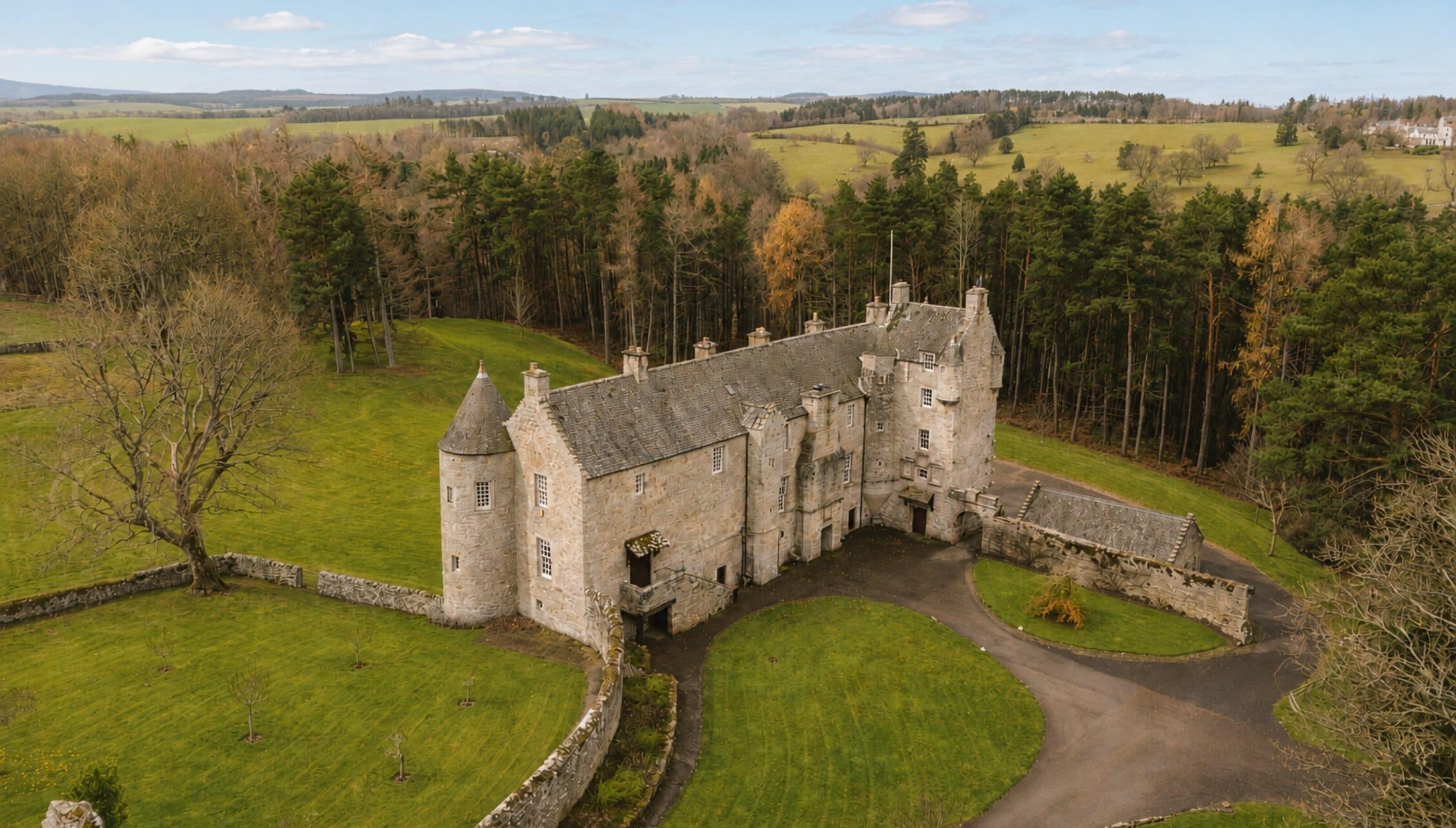 Ferniehirst Castle, Scottish Borders – Stone castle with round towers surrounded by green grounds and coniferous woodland.