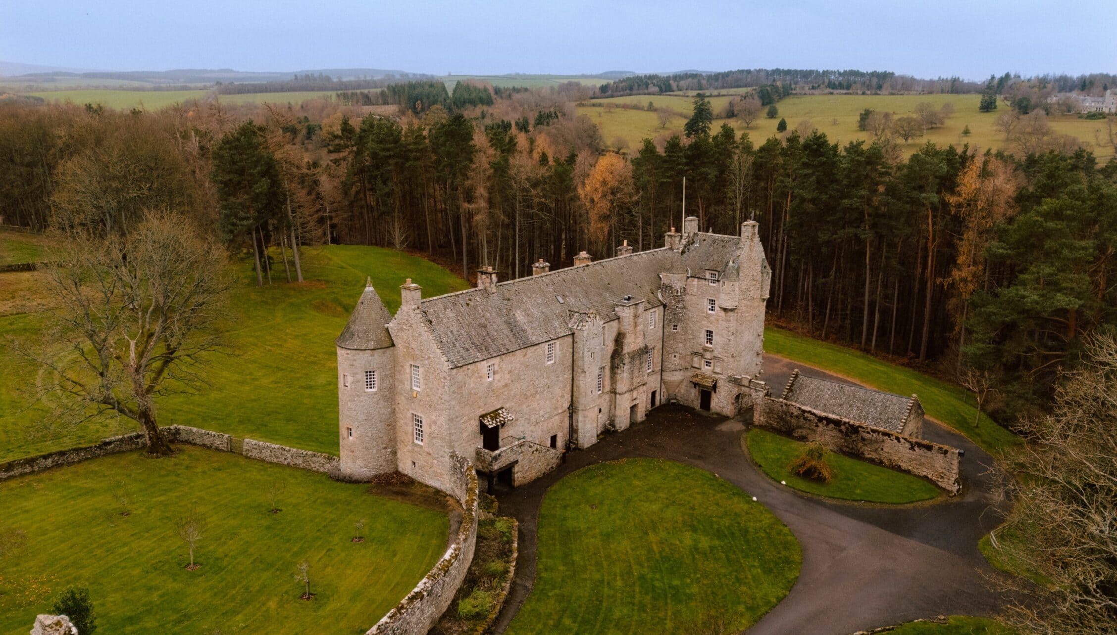 Ferniehirst Castle, East Lothian – Stone castle with conical towers surrounded by woodland and rolling farmland.