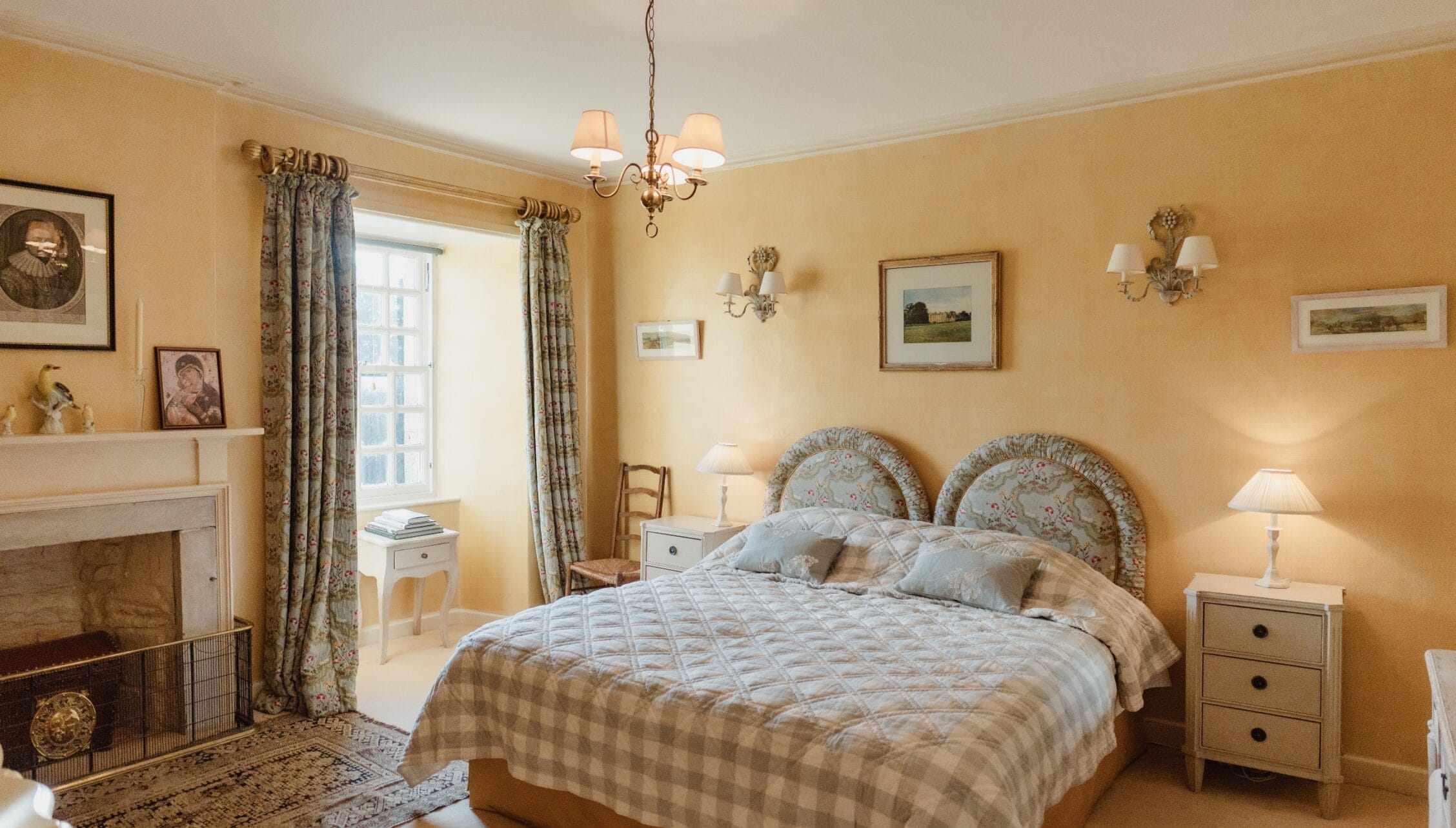 Ferniehirst Castle, East Lothian – Double bed with patterned headboard in yellow-walled bedroom with fireplace.
