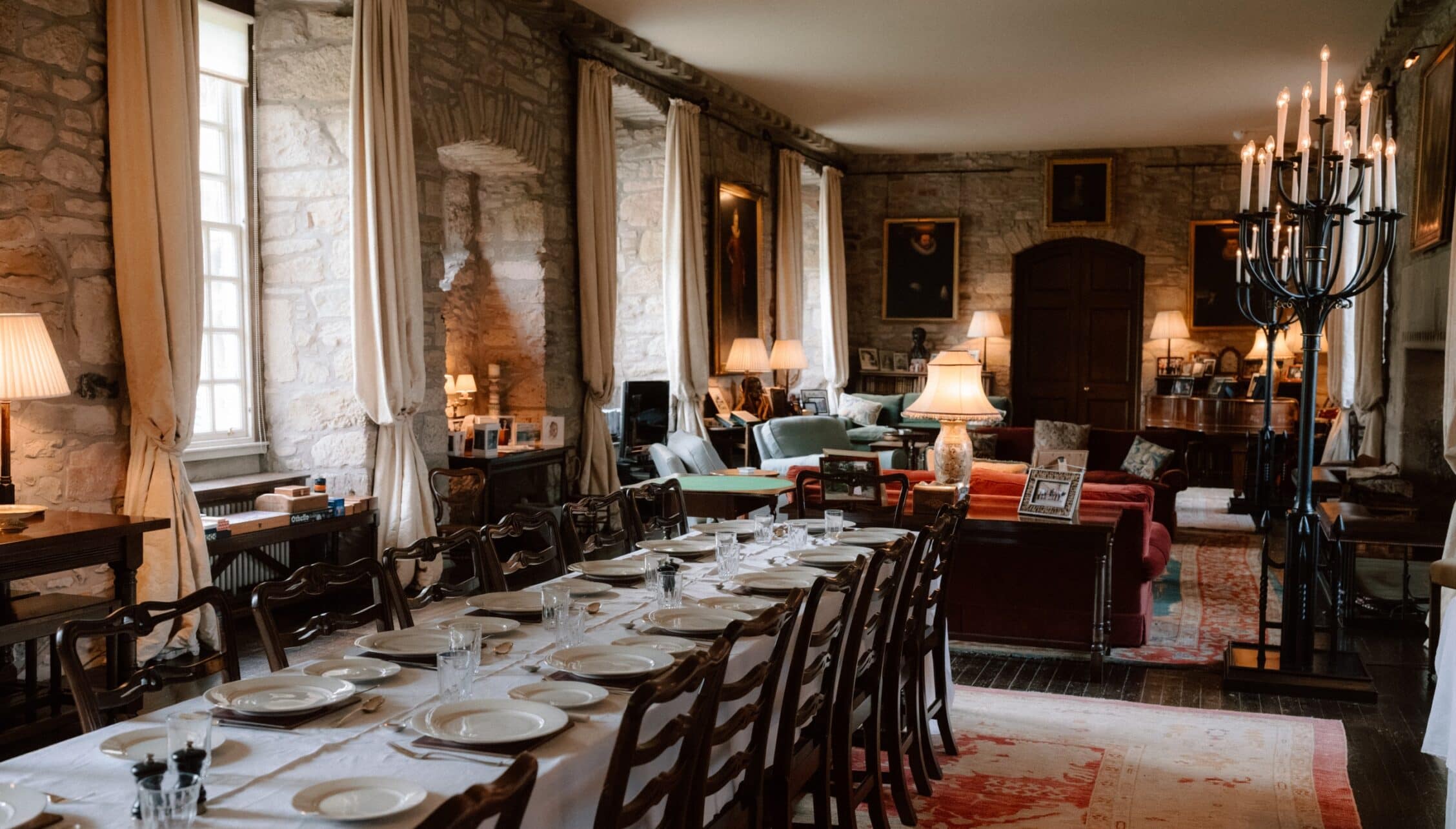 Ferniehirst Castle, East Lothian – Formal dining room with stone walls, set dining table and black candelabra.