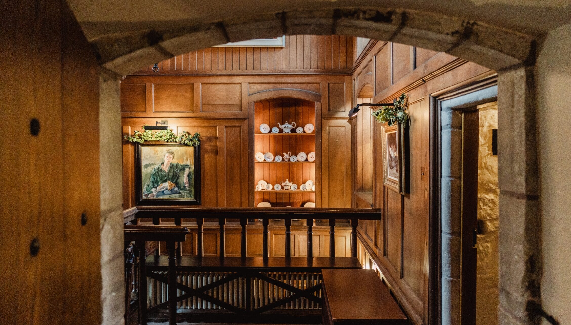 Ferniehirst Castle, East Lothian – Wooden gallery landing with panelled walls and decorative plate shelf display.
