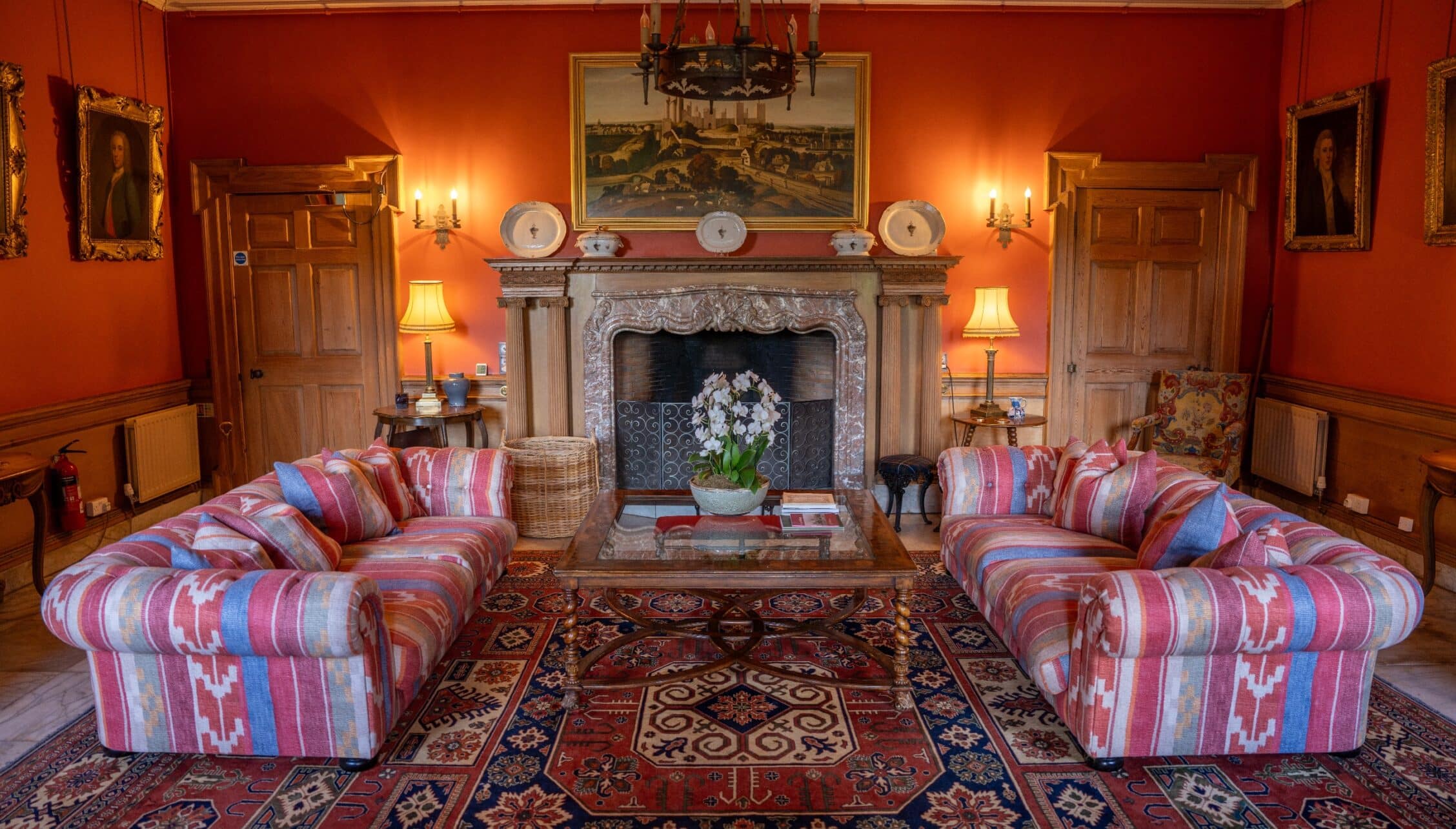 Gilmerton House, East Lothian – Formal drawing room with red walls, ornate fireplace, and striped sofas.