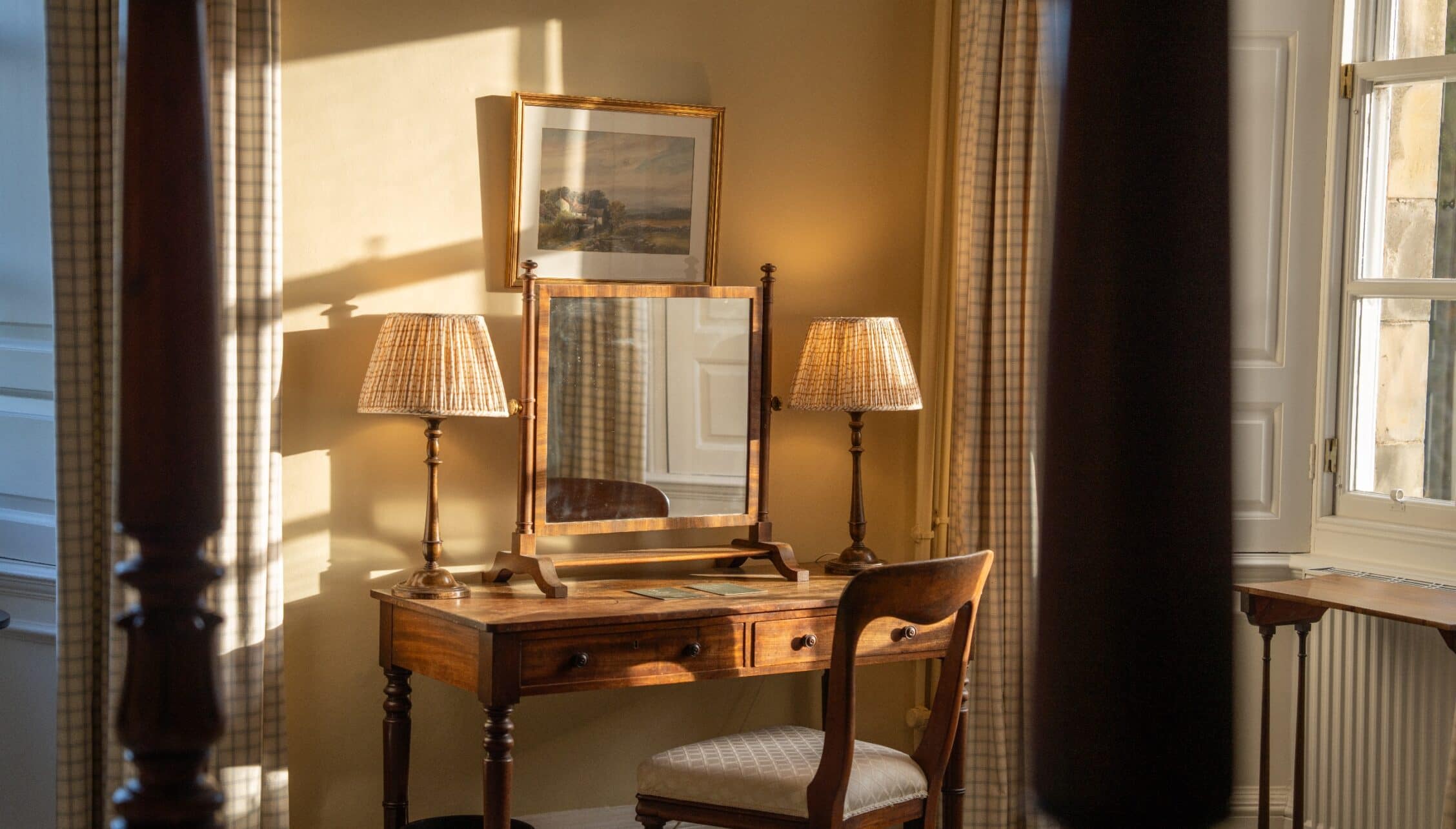 Gilmerton House, East Lothian – Bedroom dressing table with wooden mirror, table lamps, and sash window with countryside view.