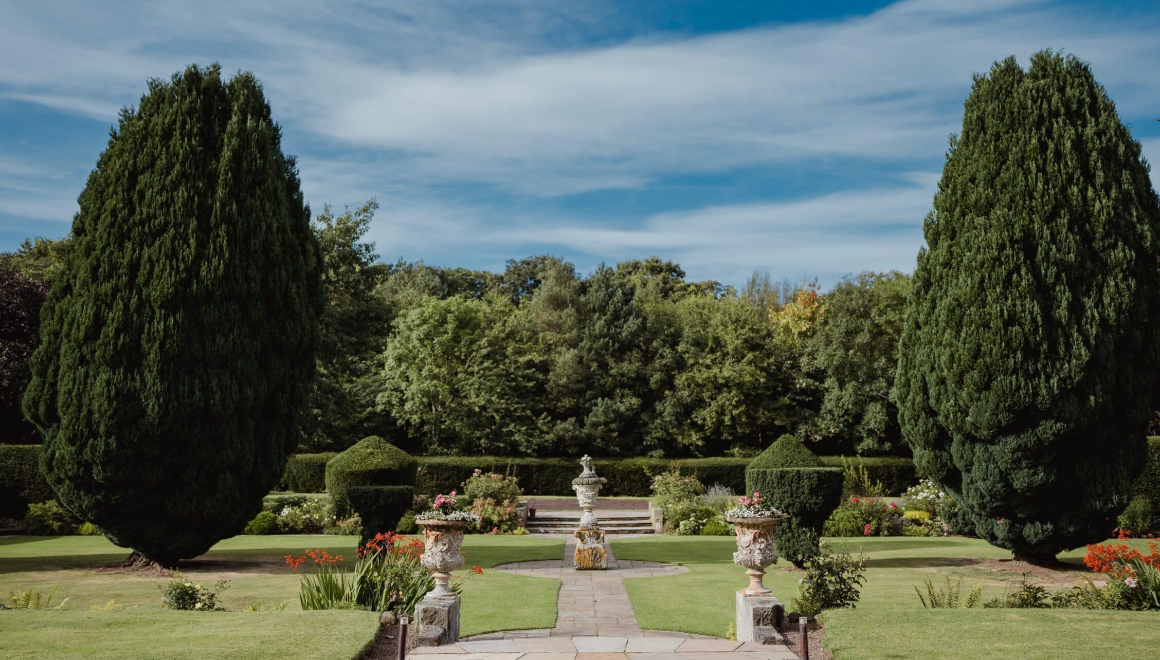 Gilmerton House, East Lothian – Formal gardens with tall columnar conifers, stone urns, and ornamental fountain.
