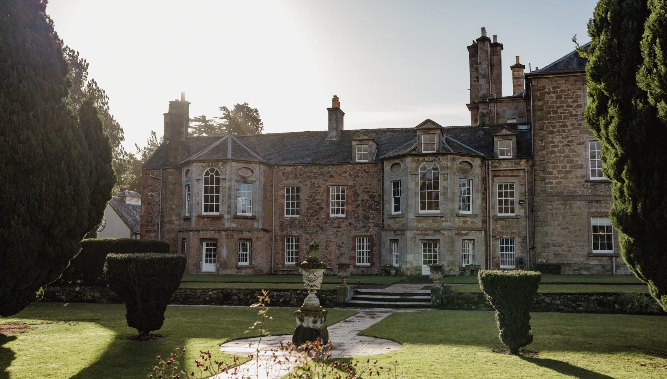 Gilmerton House, East Lothian – Stone country house with manicured lawns, topiary hedges, and ornamental urn.