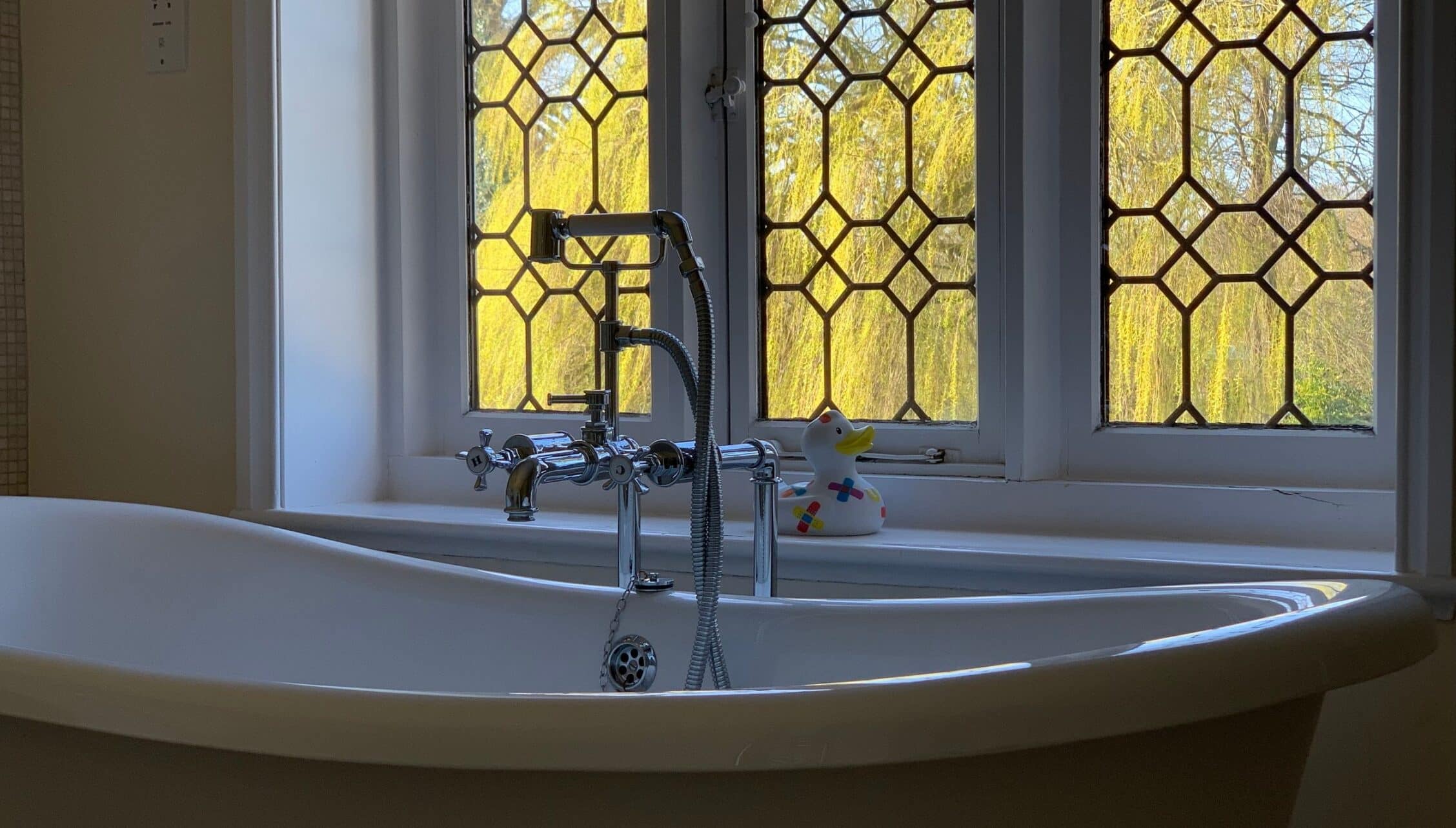 Hill House Norfolk, Norfolk – Freestanding bath with chrome taps and leaded windows overlooking yellow willow trees.