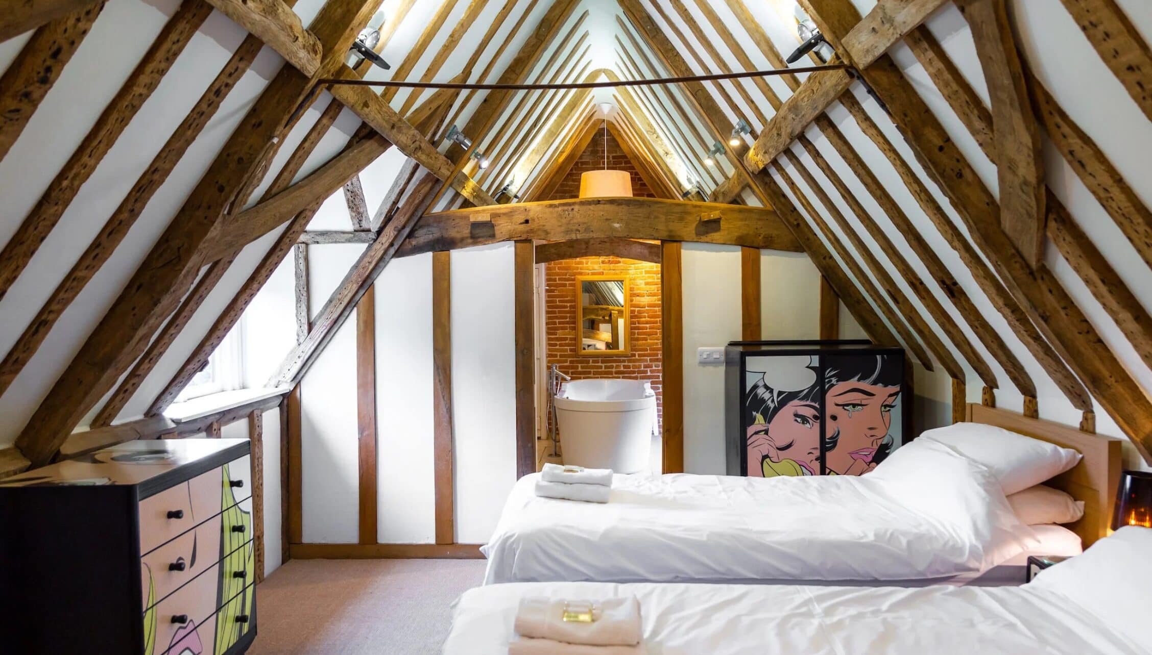 Hill House Norfolk, Norfolk – Attic bedroom with exposed timber beams, ensuite bathroom and contemporary artwork.