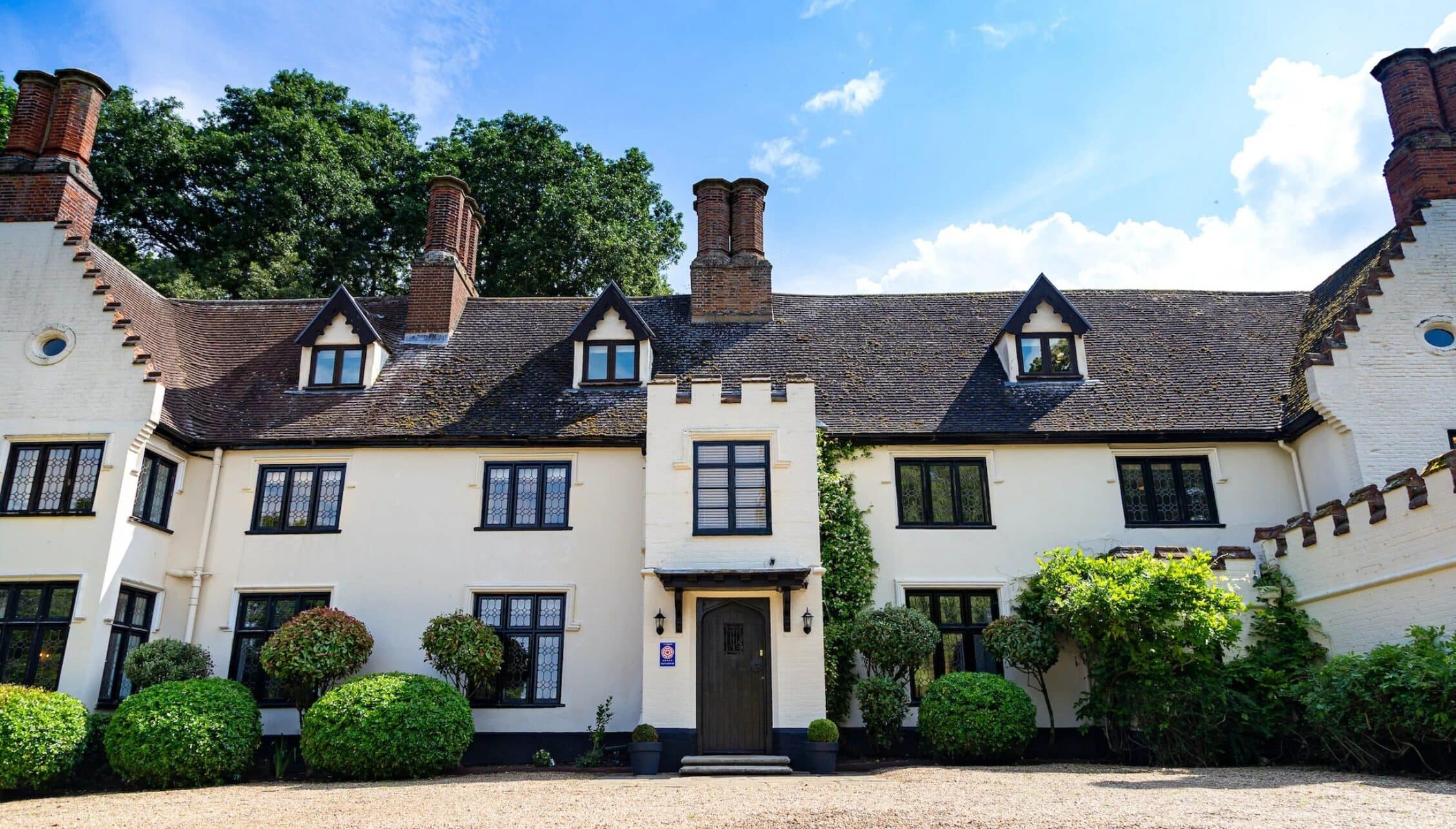 Hill House Norfolk, Norfolk – White-rendered country house with black casement windows and multiple brick chimneys.