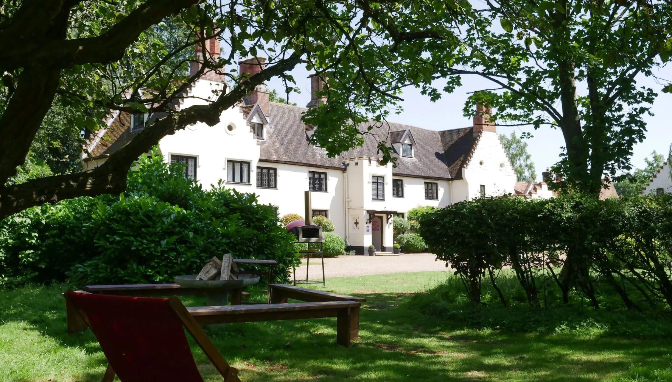 Hill House Norfolk, Norfolk – White rendered country house with red brick chimneys, viewed from gardens with mature trees.