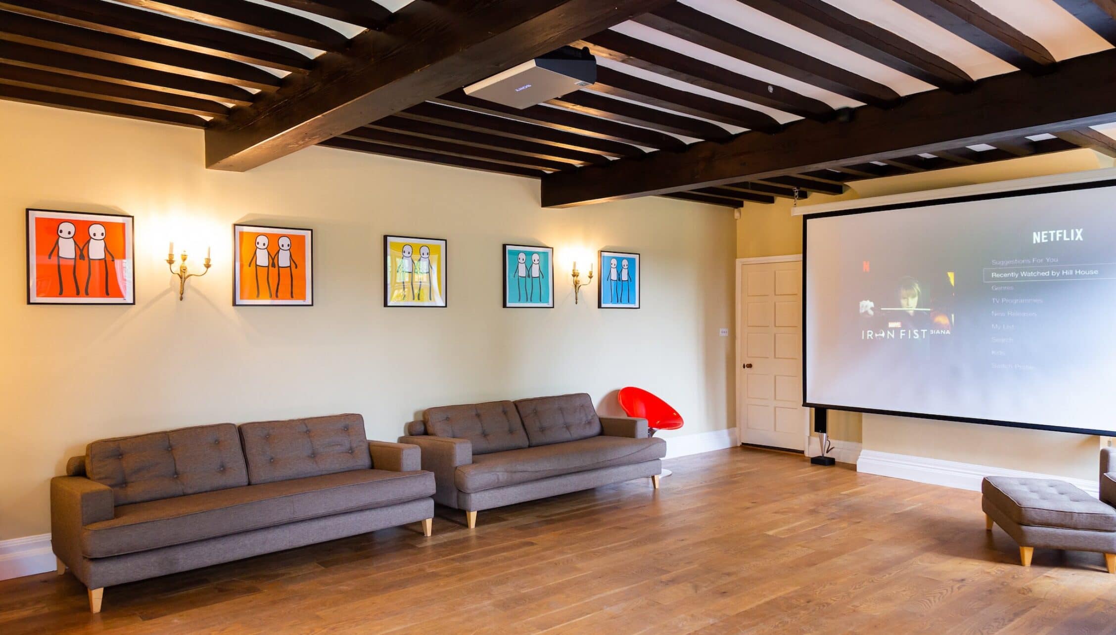 Hill House Norfolk, Norfolk – Cinema room with grey sofas, exposed beams and projection screen displaying Netflix.