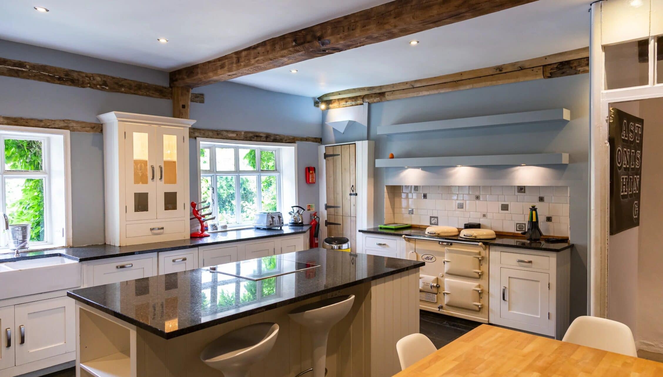 Hill House Norfolk, Norfolk – Spacious kitchen with exposed wooden beams, cream Aga cooker and dark granite worktops.