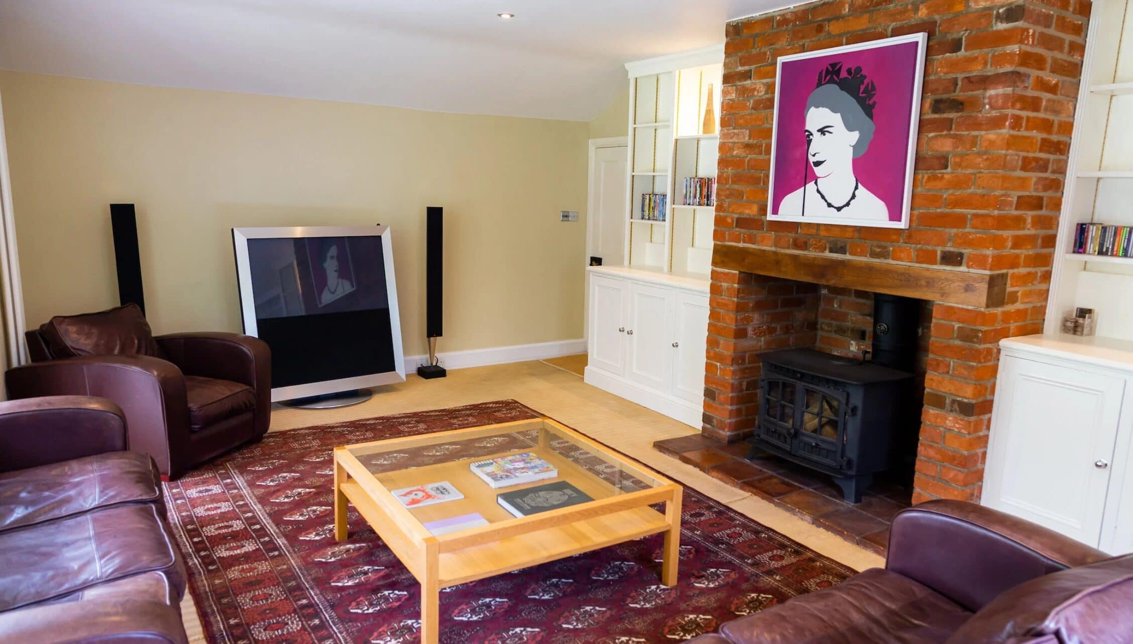 Hill House Norfolk, Norfolk – Spacious living room with exposed red brick fireplace, wood stove, and leather seating.