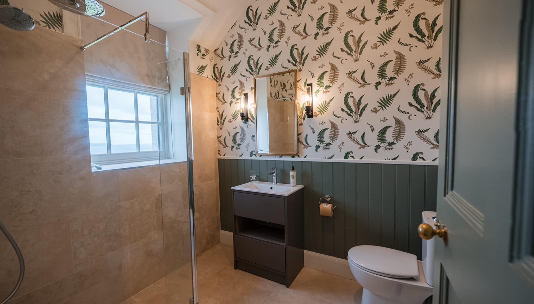 House of the Northern Gate, Highland – Modern bathroom with fern-patterned wallpaper, walk-in shower and black vanity unit.
