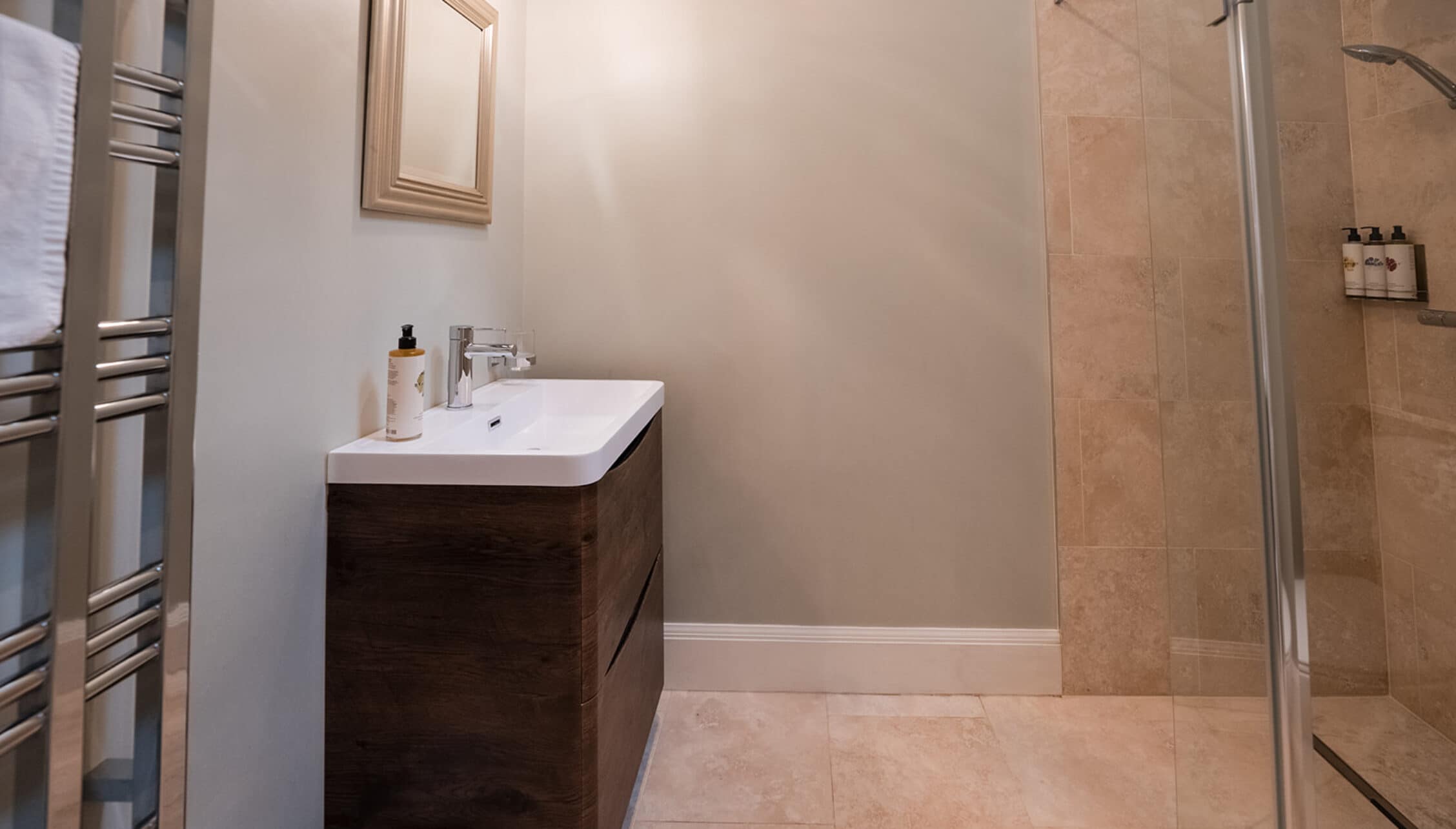 House of the Northern Gate, Highland – Modern bathroom with dark wood vanity, white sink, and walk-in shower enclosure.