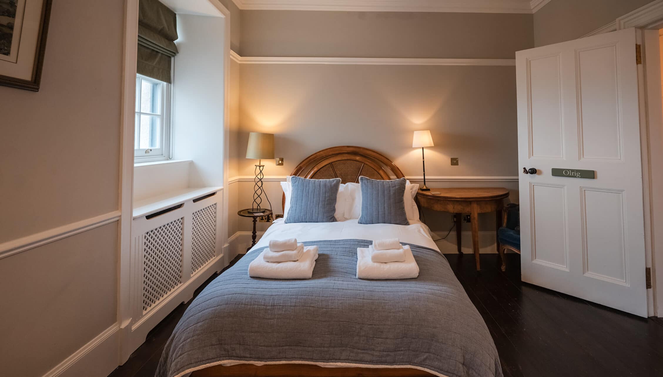 House of the Northern Gate, Highland – Bedroom with wooden-framed bed, blue linen bedding, and white folded towels.