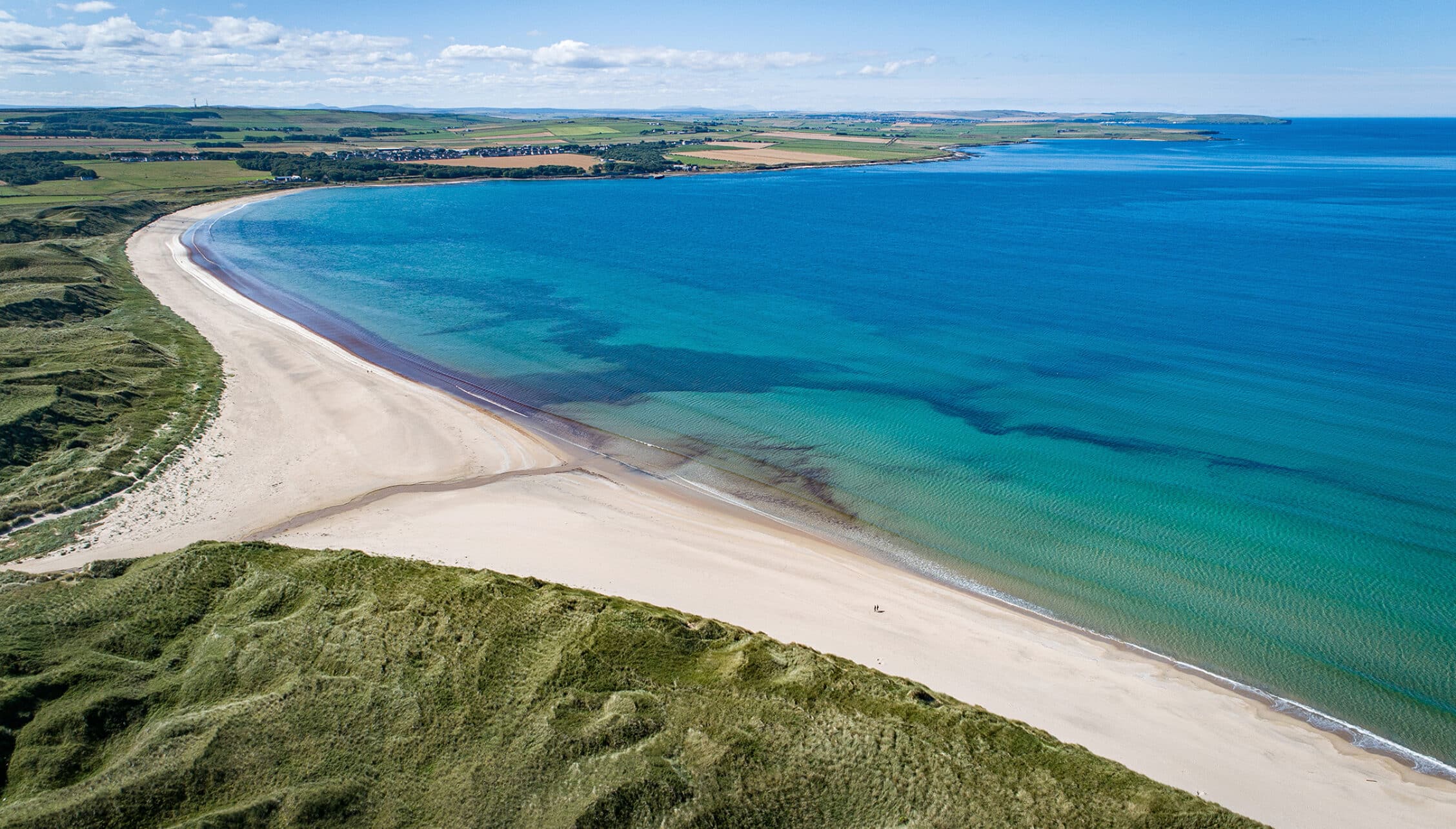 House of the Northern Gate, Highland – Aerial view of curved sandy beach, turquoise sea and green moorland coastline.