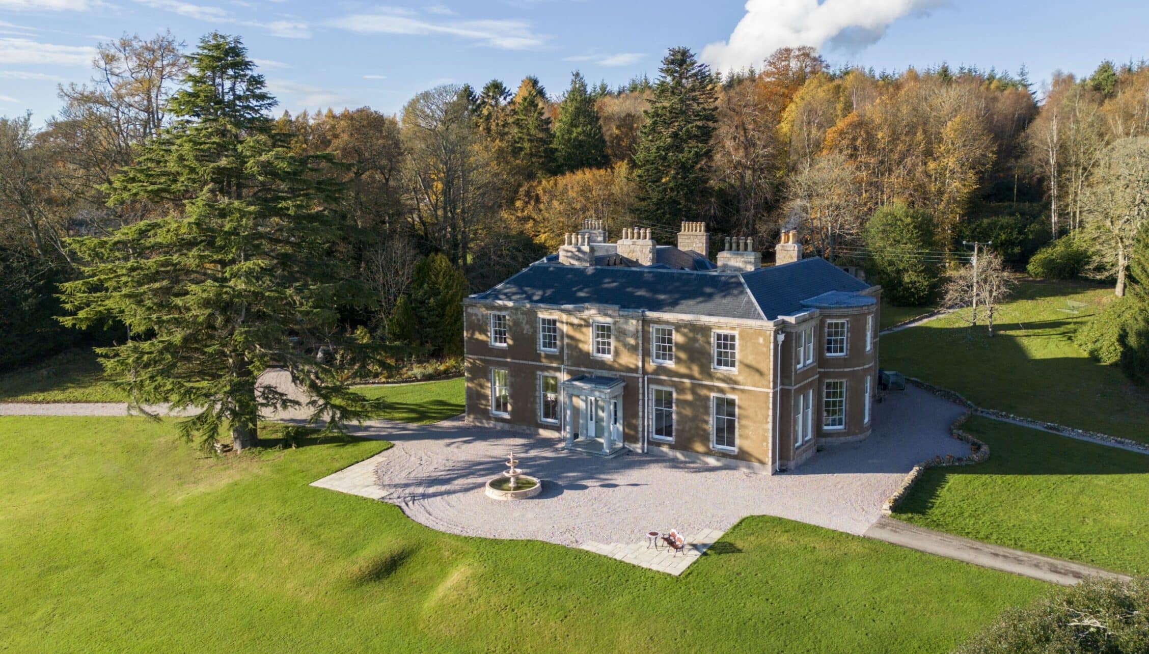 Manar House, Aberdeenshire – Georgian stone mansion with blue roof and chimney stacks, surrounded by autumn woodland and manicured lawns.