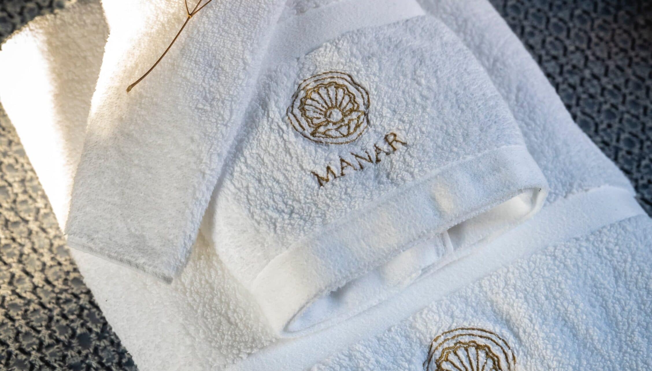 Manar House, Aberdeenshire – Folded white towels with embroidered Manar House logo and leaf motif.
