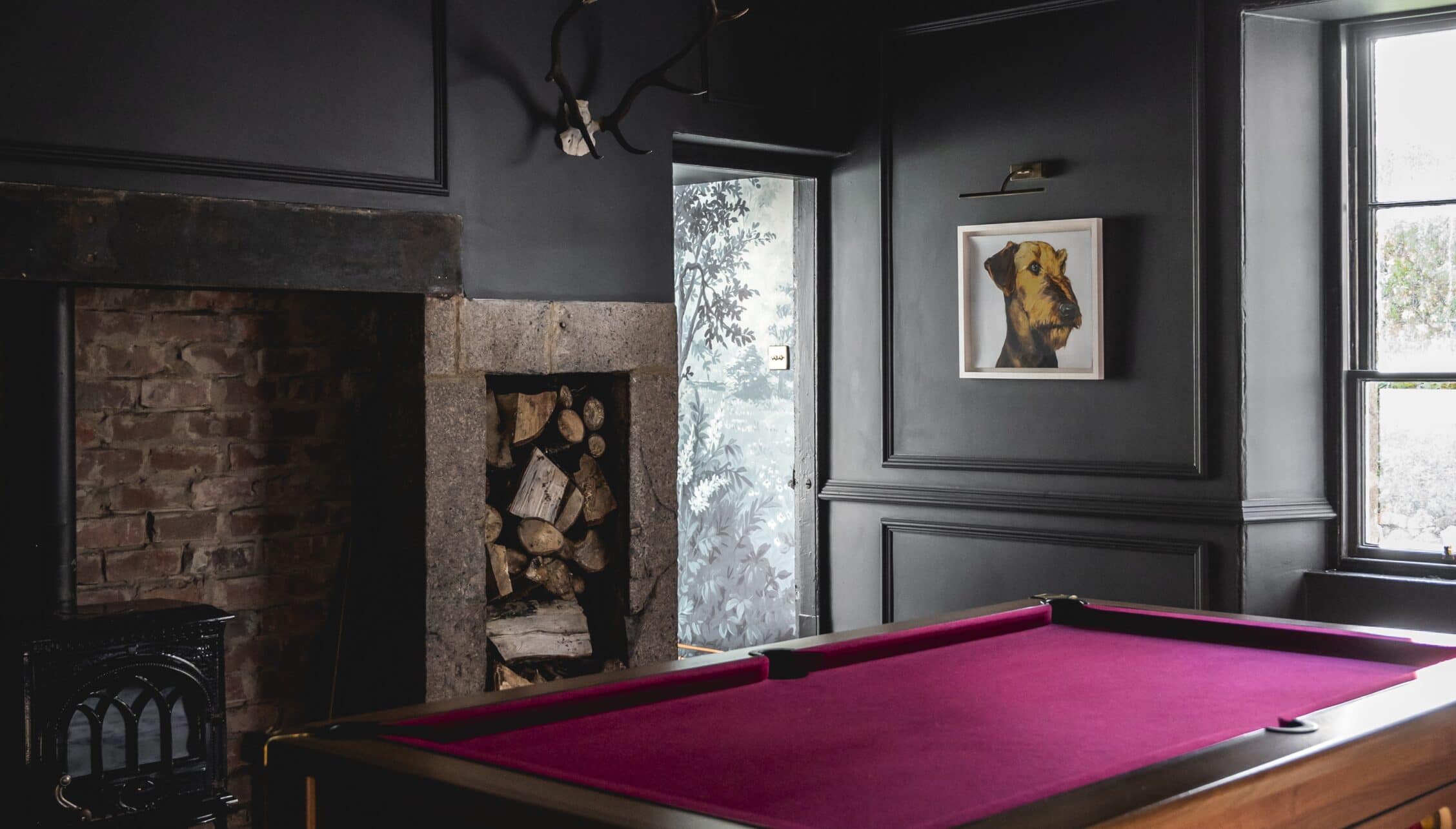 Manar House, Aberdeenshire – Charcoal-walled games room with pink pool table and brick fireplace.