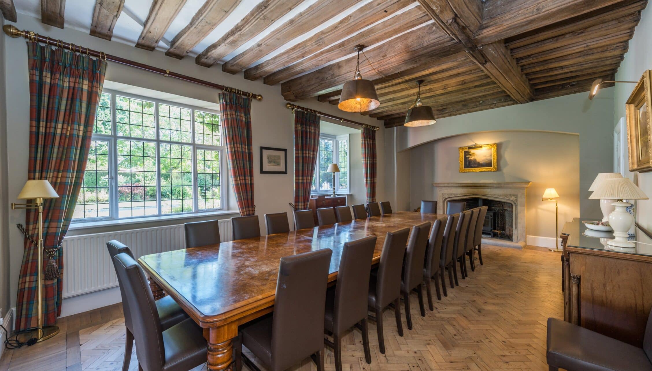 Nedging Hall, Suffolk – Formal dining room with exposed wooden beams and polished wood table seating fourteen.