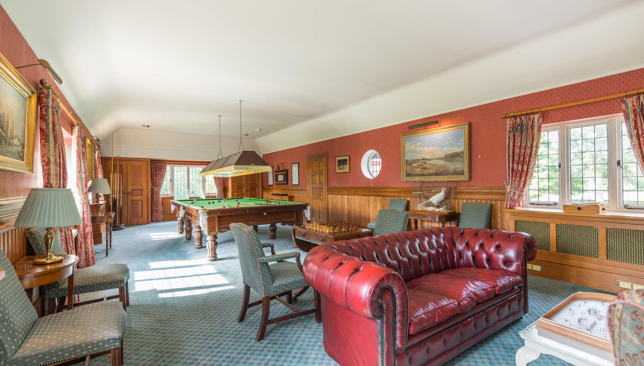 Nedging Hall, Suffolk – Games room with red leather Chesterfield sofa, pool table, and wood panelling.