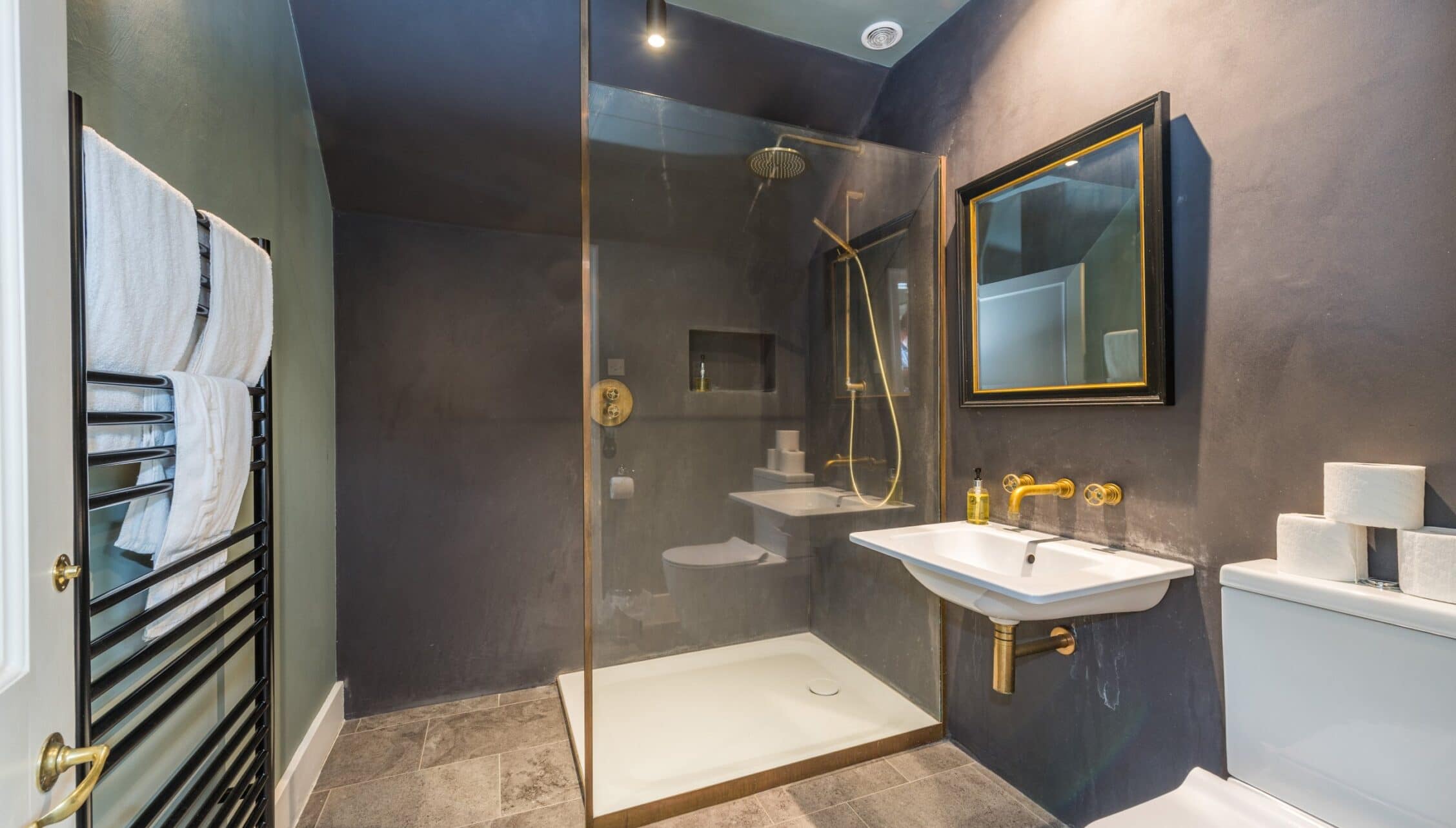 Nedging Hall, Suffolk – Modern bathroom with walk-in shower, brass fixtures, and heated towel rail.