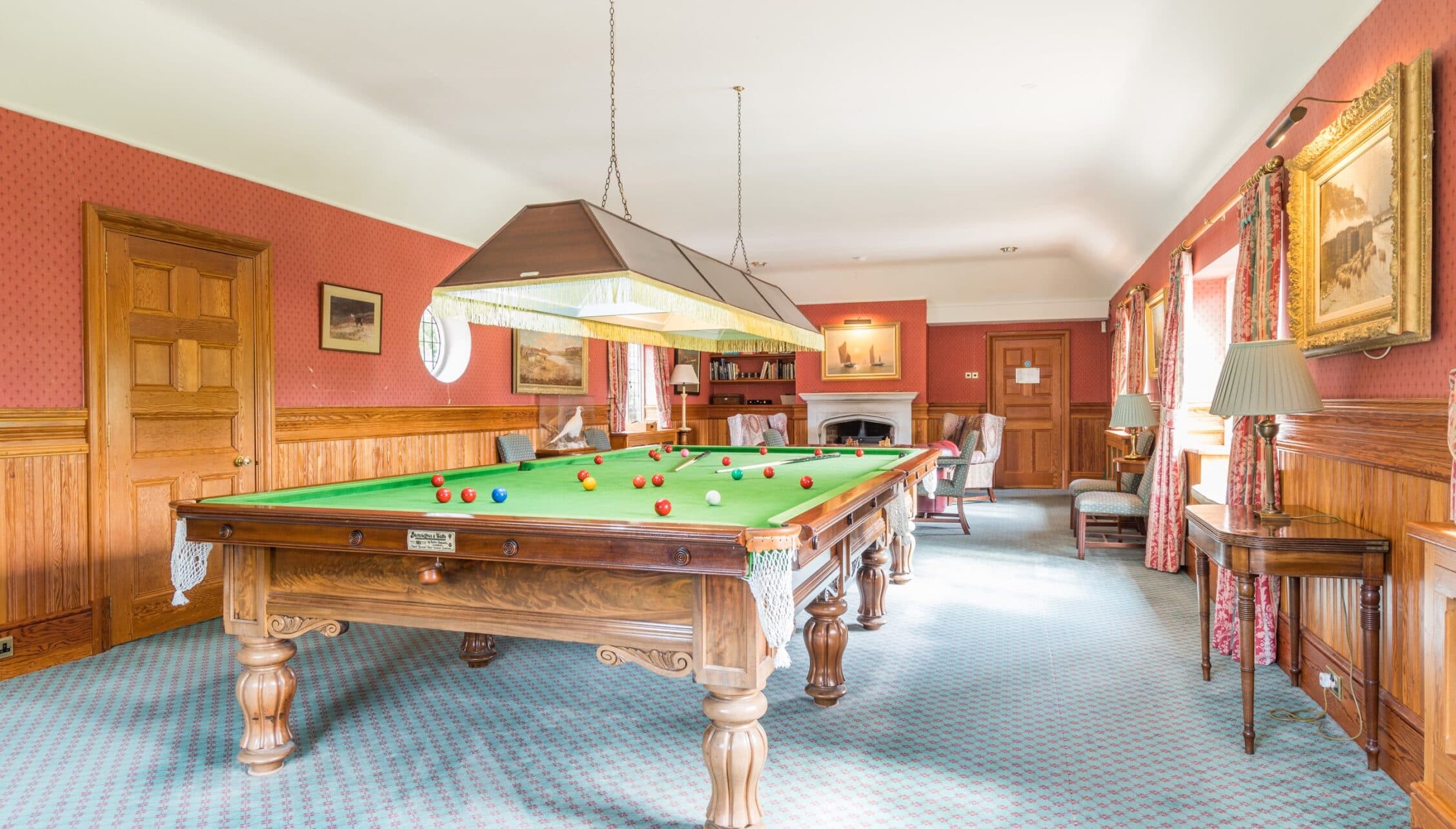 Nedging Hall, Suffolk – Snooker room with Victorian billiards table, red walls and wooden panelling.