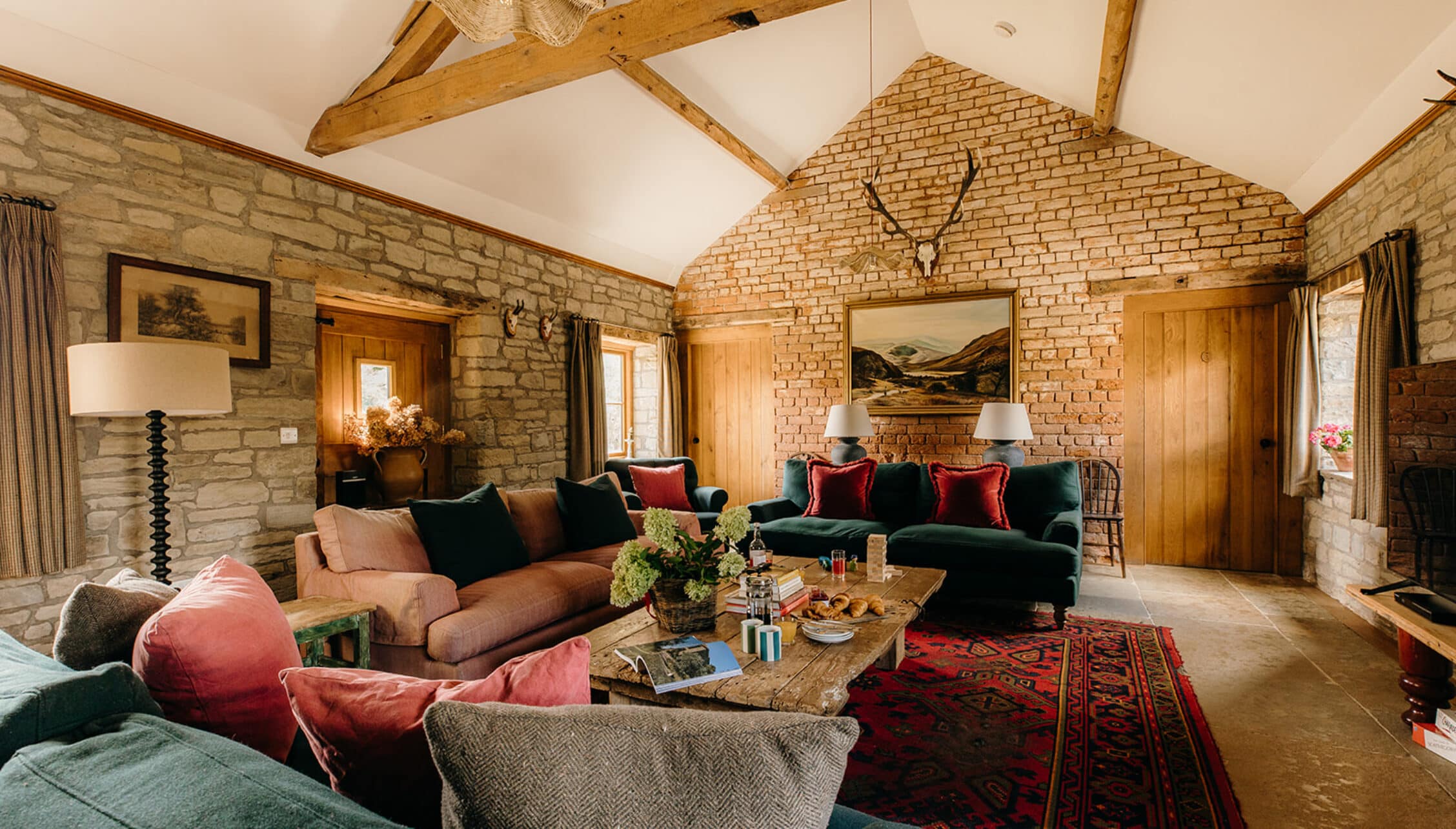 The Barns – Exclusive Hire, Herefordshire – Spacious open-plan living room with exposed brick walls, wooden beams and vaulted ceiling.