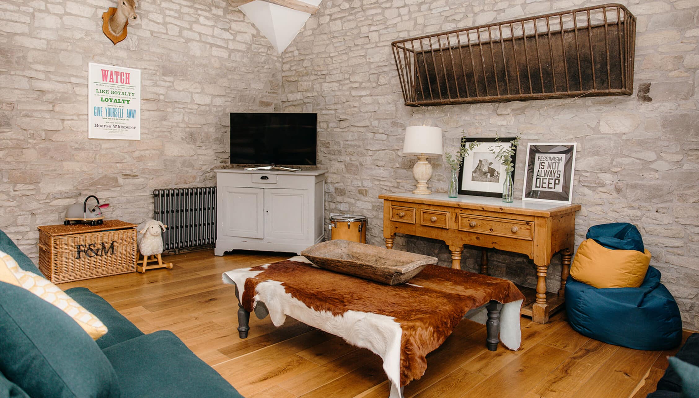 The Barns – Exclusive Hire, Herefordshire – Stone barn interior with wooden flooring, cowhide bench and exposed brick walls.