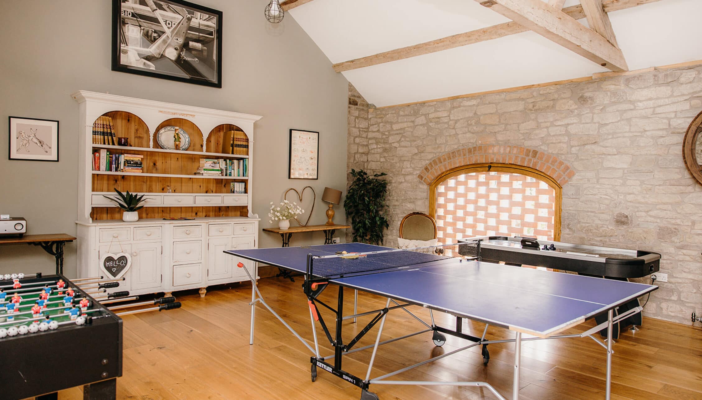 The Barns – Exclusive Hire, Herefordshire – Games room with table tennis, foosball table and exposed stone fireplace.