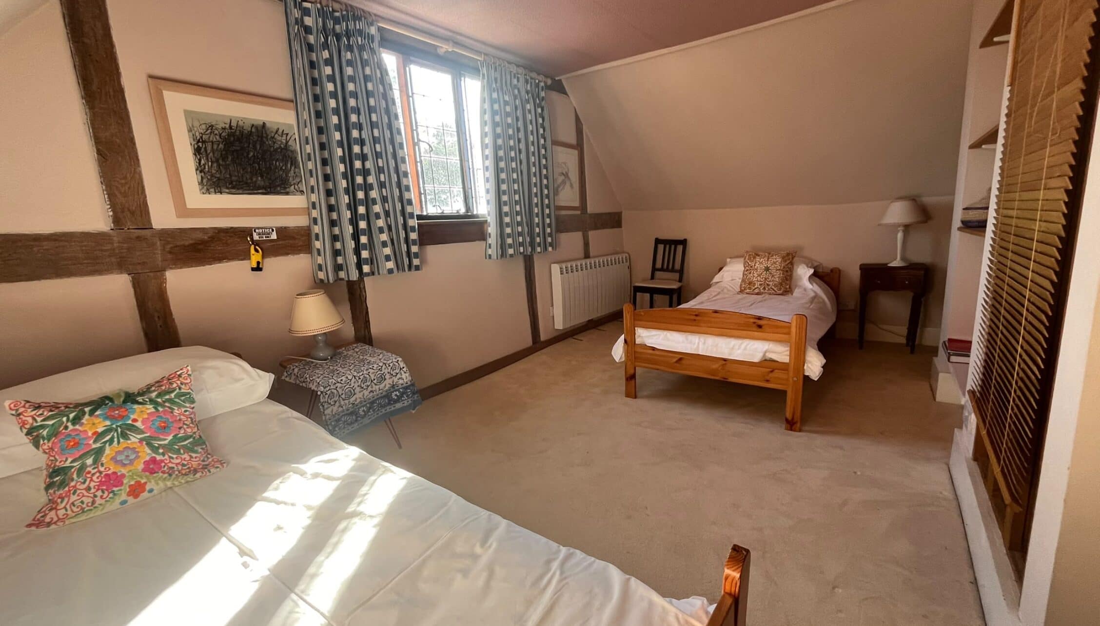 The Long House, West Sussex – Spacious attic bedroom with exposed timber beams and twin beds.