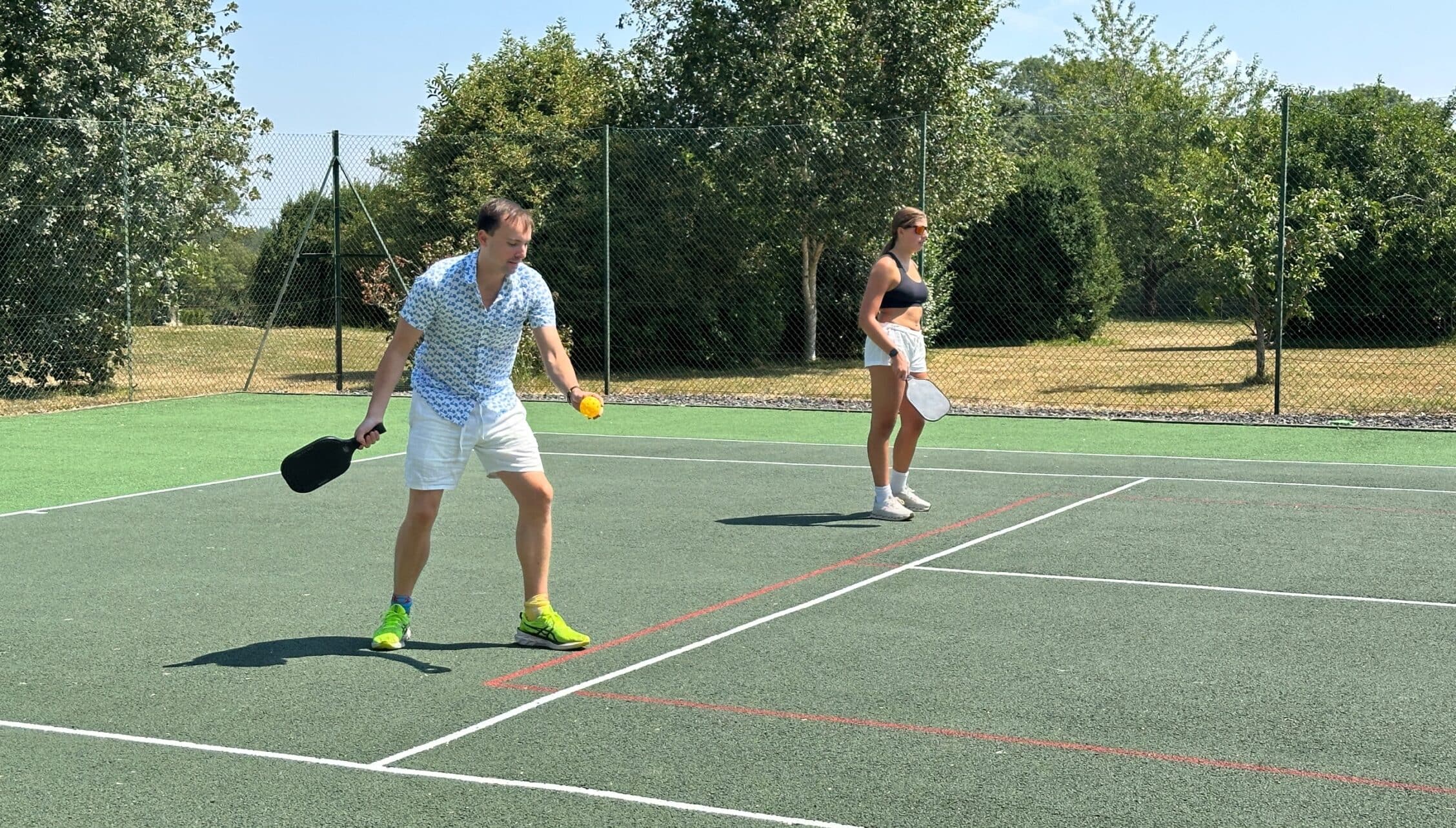 The Old House, Hampshire – Two guests playing pickleball on outdoor court with net and tree-lined boundaries.
