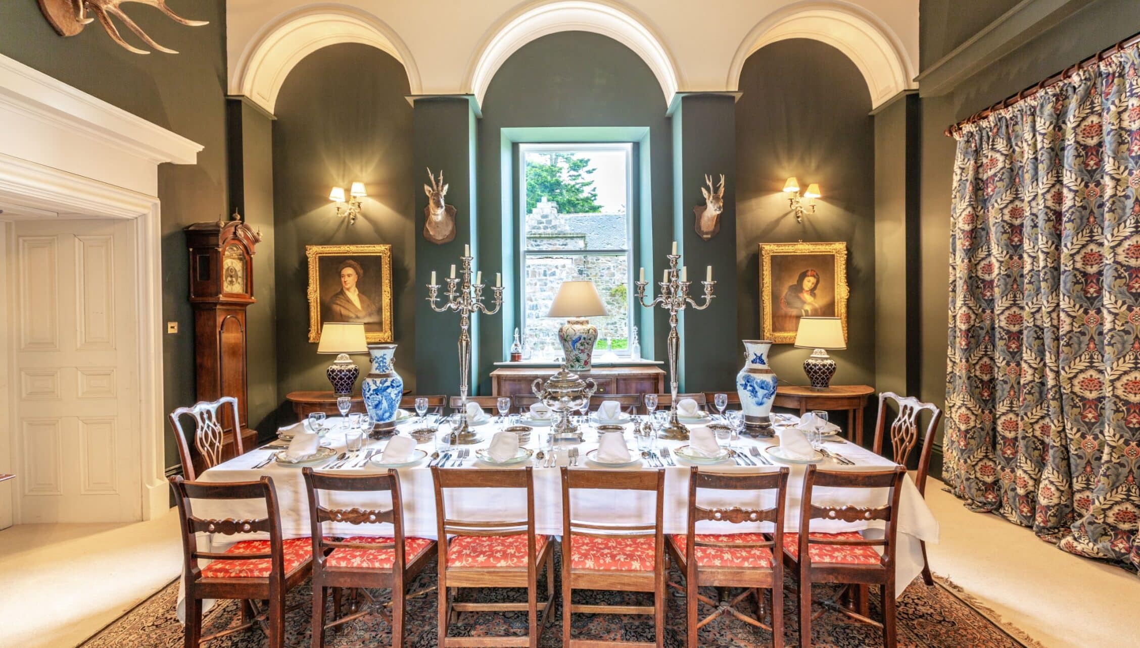 Wardhill Castle, Aberdeenshire – Formal dining room with arched ceiling, blue-grey walls, and antique portraits.