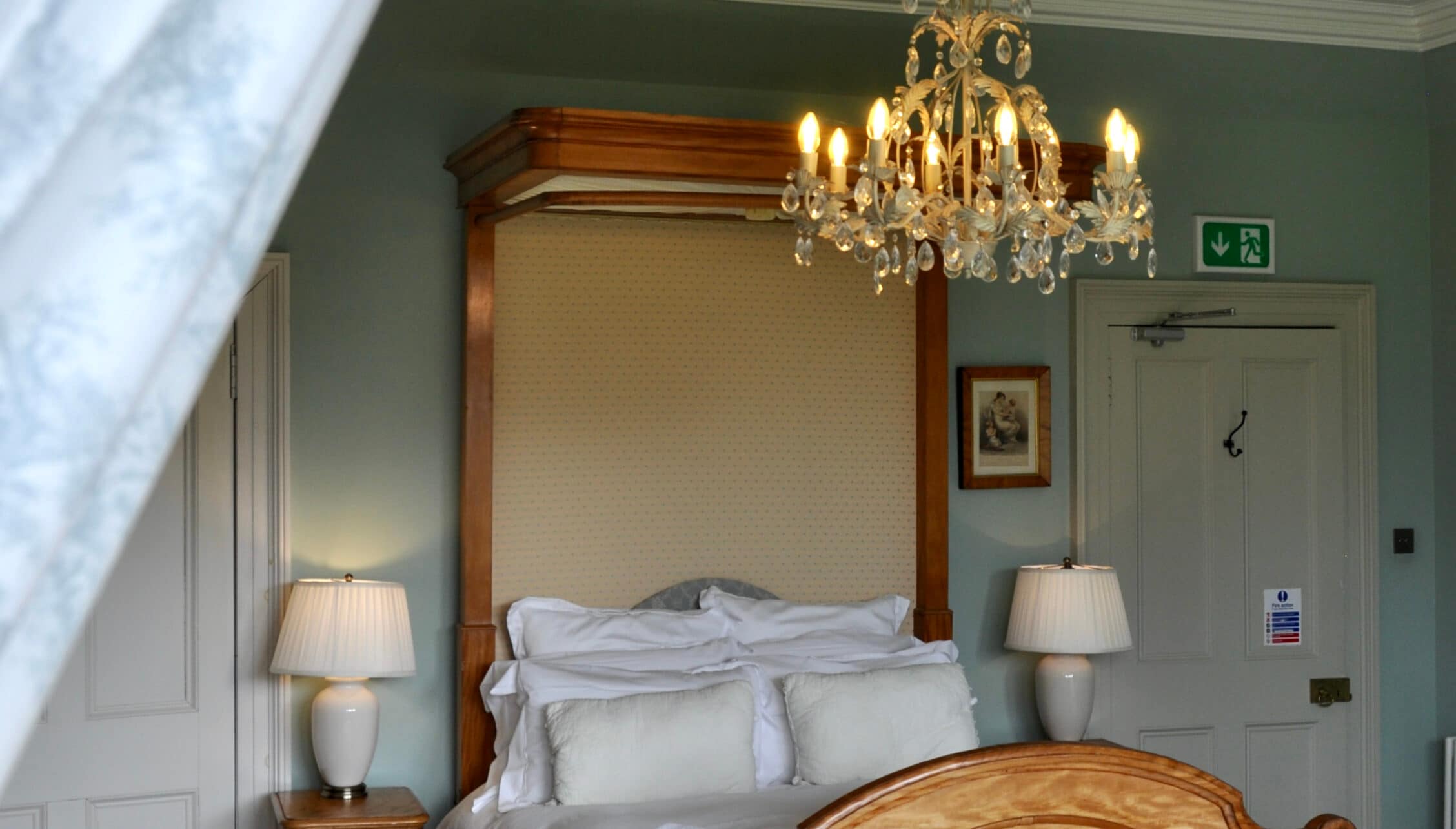 Wardhill Castle, Aberdeenshire – Four-poster bed with wooden frame, crystal chandelier, sage green walls, bedside lamps.
