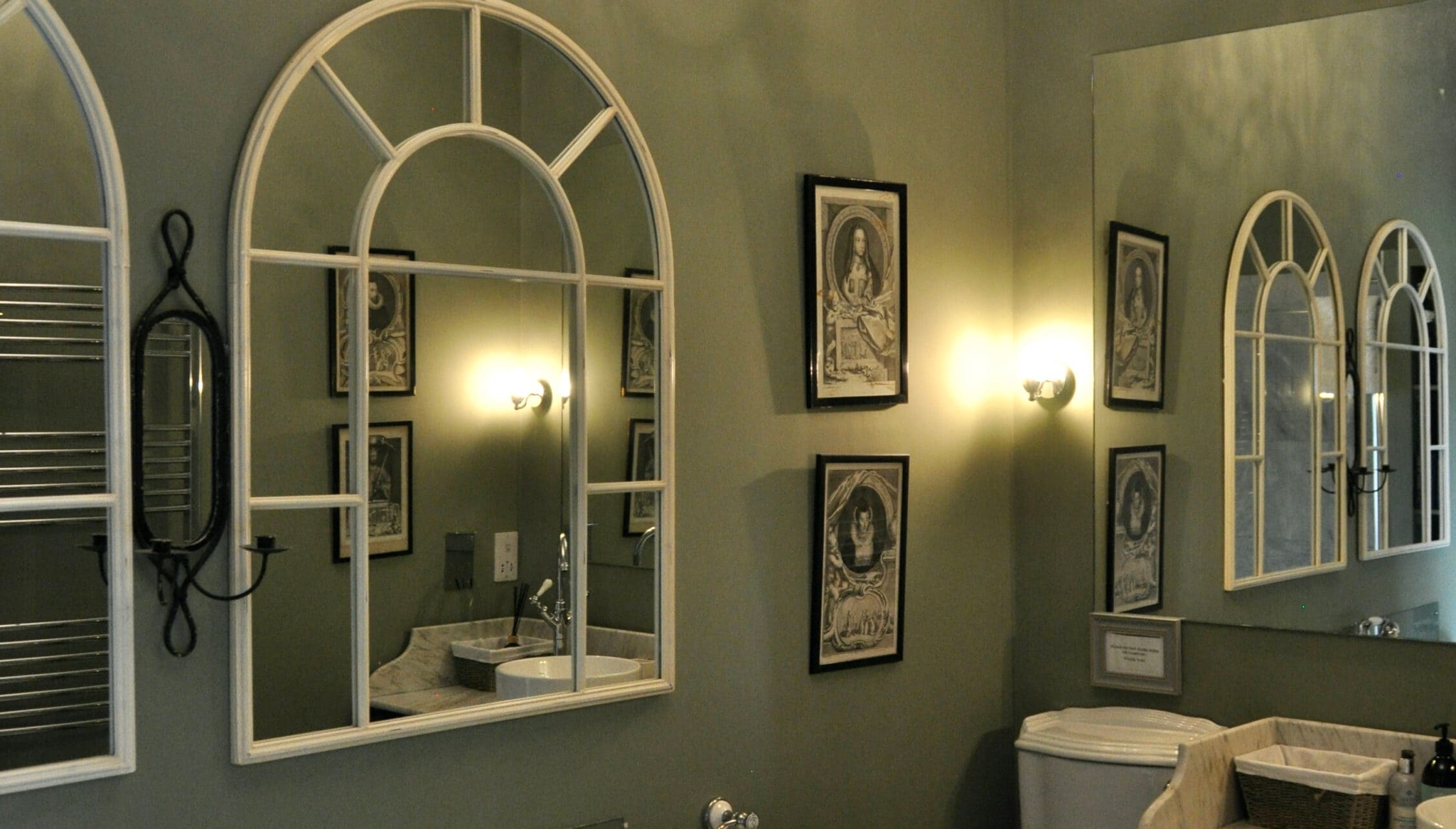 Wardhill Castle, Aberdeenshire – Bathroom with arched mirror cabinets and framed religious artwork on sage green walls.