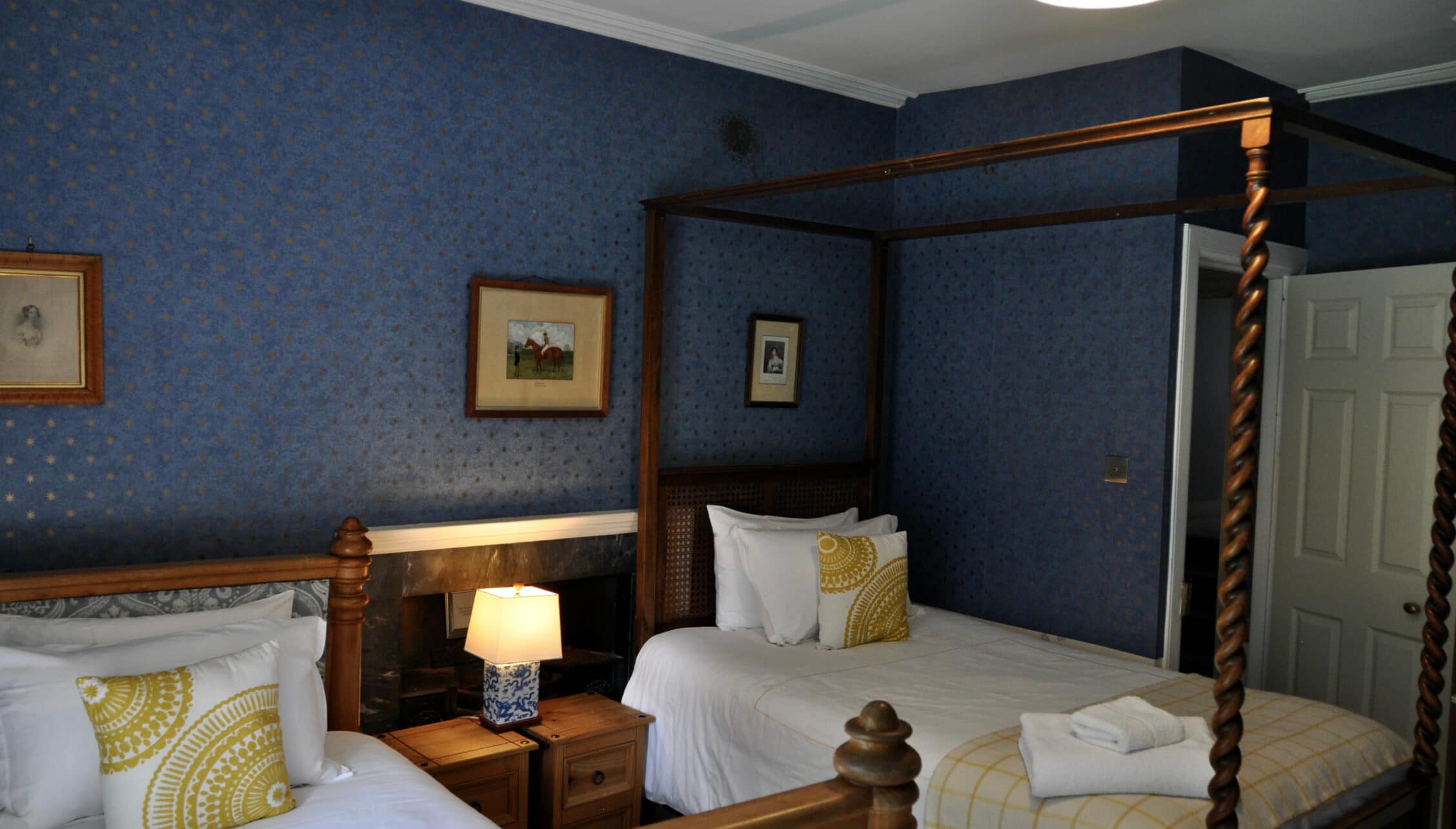 Wardhill Castle, Aberdeenshire – Bedroom with twin four-poster beds and blue patterned wallpaper.