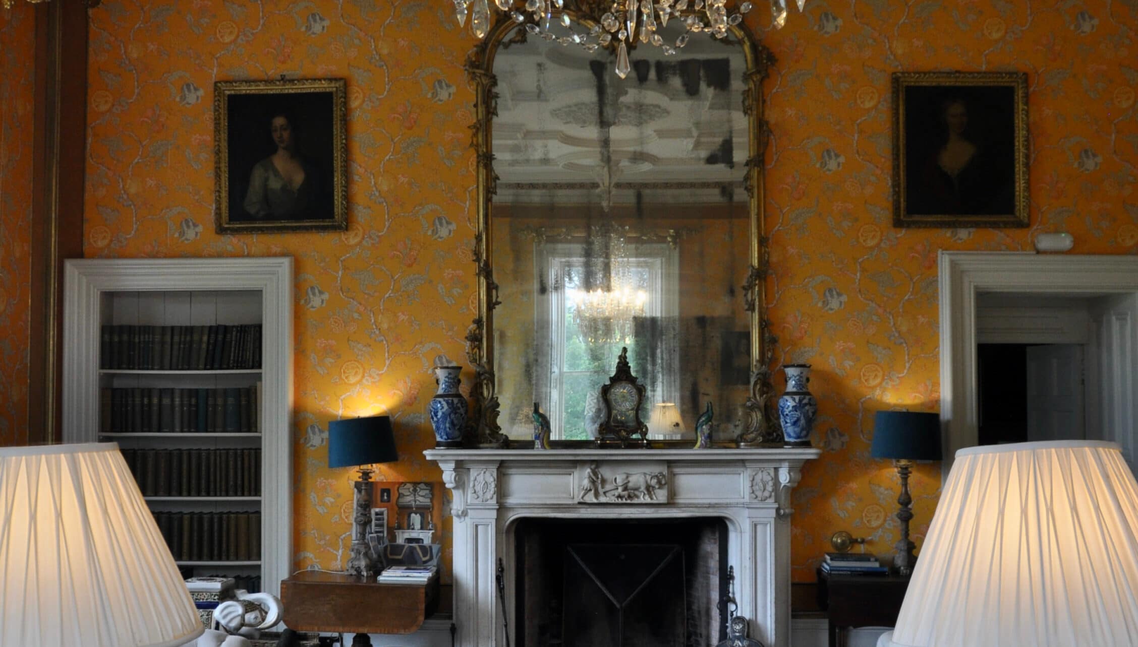 Wardhill Castle, Aberdeenshire – Drawing room with ornate mustard wallpaper, white marble fireplace and decorative mirror.