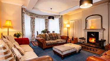 Brookside, Herefordshire – Spacious lounge with leather Chesterfield sofa, wood-burning stove and bay windows.