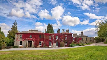 Colehayes Park – Red-ivy-clad country house with stone façade and manicured lawns.