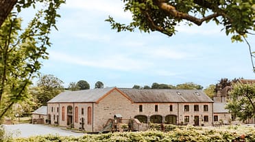 The Barns – The Old Mill, Hayloft & Byre, Herefordshire – Converted stone barn with red brick detailing, slate roof, surrounded by mature trees and.