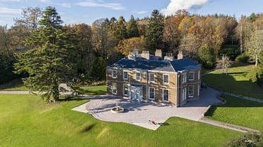 Manar House, Aberdeenshire – Georgian stone mansion with blue roof and chimney stacks, surrounded by autumn woodland and manicured lawns.