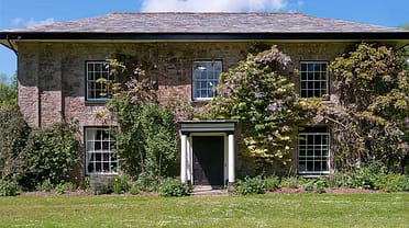 Old Rectory and Coach House – Stone country house with ivy-covered façade, sash windows and wisteria flowering climbers.