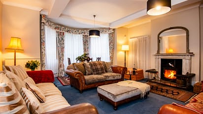 Brookside, Herefordshire – Spacious lounge with leather Chesterfield sofa, wood-burning stove and bay windows.