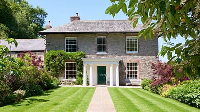 Gitcombe House, Devon – Stone Georgian house with white portico, manicured lawn, and flowering shrubs.