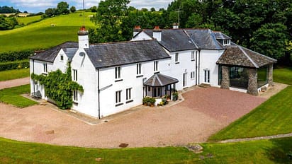 Monnow Valley Studio, Monmouthshire – White rendered country house with slate roof and gravel driveway surrounded by rolling green fields.