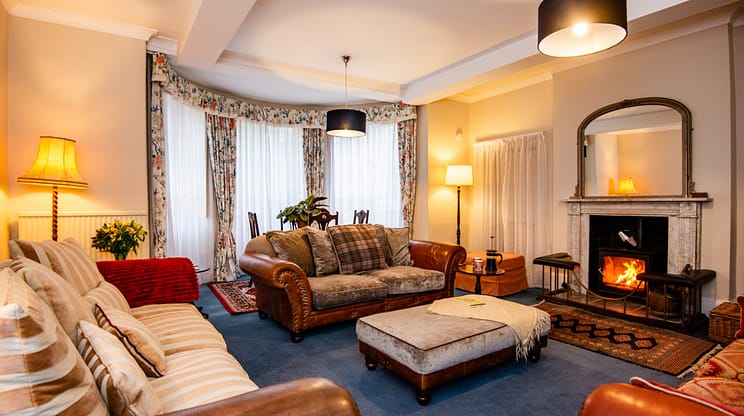 Brookside, Herefordshire – Spacious lounge with leather Chesterfield sofa, wood-burning stove and bay windows.