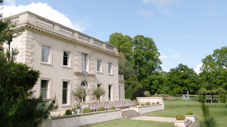 The Location House, Warwickshire – Neoclassical stone house with balustraded roofline, manicured gardens and open parkland grounds.