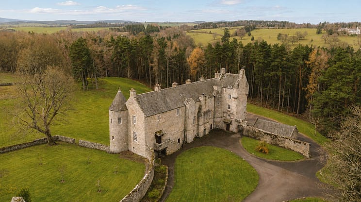 Ferniehirst Castle, Scottish Borders – Stone castle with round towers surrounded by green grounds and coniferous woodland.