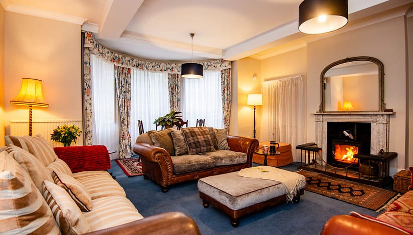 Brookside, Herefordshire – Spacious lounge with leather Chesterfield sofa, wood-burning stove and bay windows.